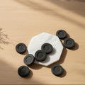 charcoal tablets on a white plate with a book and plant on a wooden board